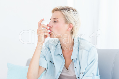 Pretty blonde woman using her inhaler