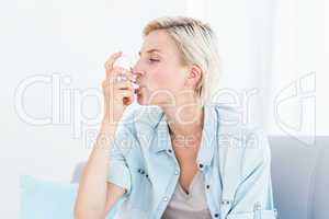 Pretty blonde woman using her inhaler