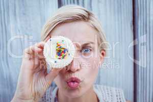 Pretty blonde woman grimacing with cupcake