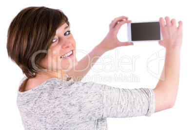 Pretty brunette looking at camera and taking a picture with her