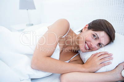 Happy woman in her bed smiling at camera