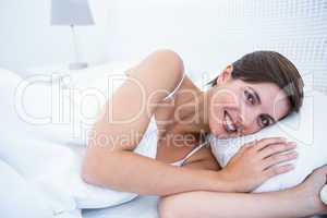 Happy woman in her bed smiling at camera