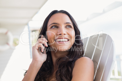 Pretty brunette sitting on a chair and calling with her mobile p