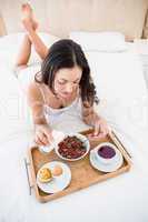 Pretty brunette eating her breakfast on bed