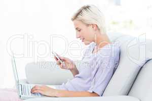 Pretty blonde woman texting with her mobile phone and using her