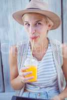 Pretty blonde woman using her tablet and drinking orange juice