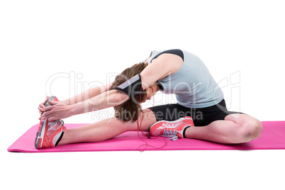 Pretty brunette stretching her leg on exercise mat