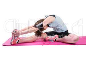 Pretty brunette stretching her leg on exercise mat