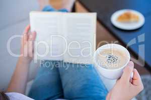 Woman reading book with cup of coffee