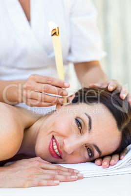 Relaxed brunette getting an ear candling treatment