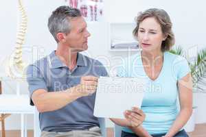 Physiotherapist showing his notes to his patient