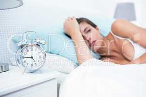 Pretty woman lying in bed with alarm clock