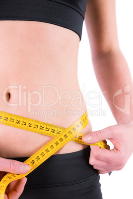 Slim woman measuring waist with tape measure