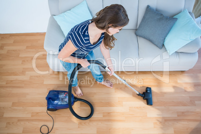 Woman using vacuum cleaner on wooden floor