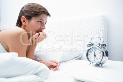 Thoughtful young woman lying in bed