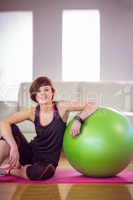 Fit woman sitting next to exercise ball