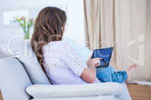 Pretty brunette using her tablet pc on couch