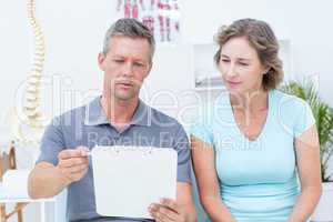 Physiotherapist reading his notes with his patient