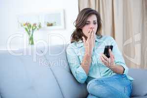 Surprised brunette looking at her smartphone