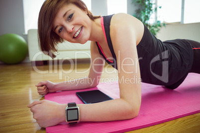 Fit woman looking at camera and doing plank on mat