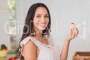 Beautiful brunette holding mini cupcake