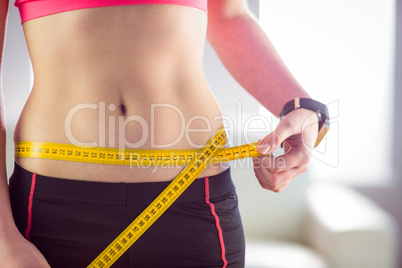 Slim woman measuring waist with tape measure