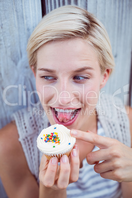 Pretty blonde woman tasting the cupcake