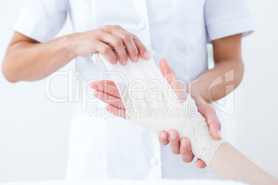 Doctor bandaging her patient wrist