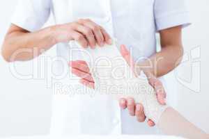Doctor bandaging her patient wrist