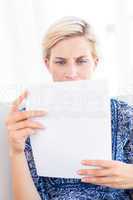 Worried blonde woman reading a paper