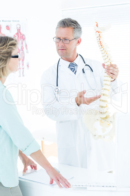 Doctor having conversation with his patient and showing spine mo