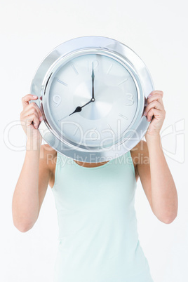 Woman holding clock in front of her head