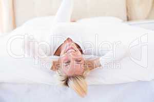 Smiling blonde woman lying on the bed
