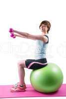 Pretty brunette exercising with dumbbells on fitness ball