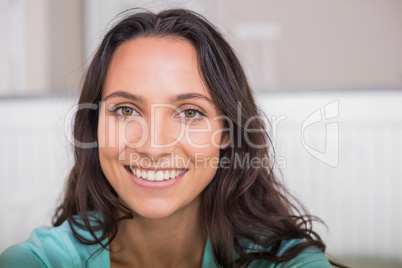 Happy brunette sitting on bed