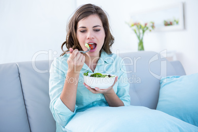 Pretty woman eating bowl of salad