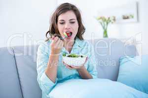 Pretty woman eating bowl of salad