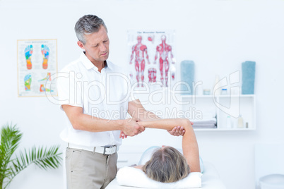 Physiotherapist examining his patients arm