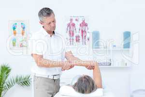 Physiotherapist examining his patients arm