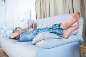 Peaceful woman lying on couch reading a book
