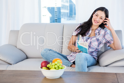 Pretty brunette looking at camera and reading a book on couch Pretty brunette looking at camera and reading a book on couch
