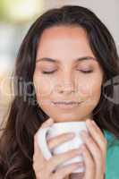Pretty brunette smelling her coffee