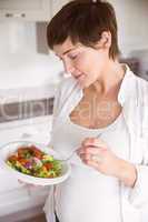 Pregnant woman having bowl of salad