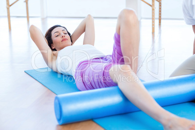 Trainer working with woman on exercise mat