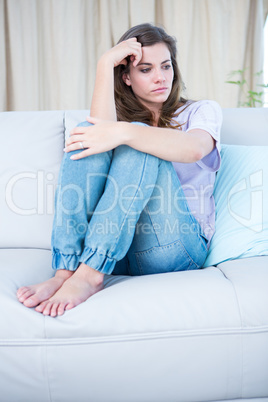 Depressed brunette sitting on her couch