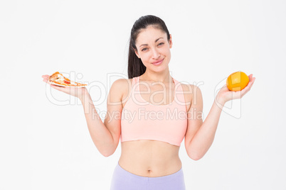 Pretty brunette holding pizza and orange