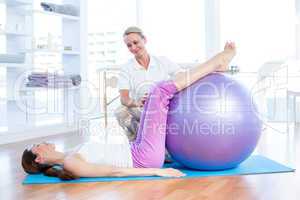 Trainer helping woman with exercise ball