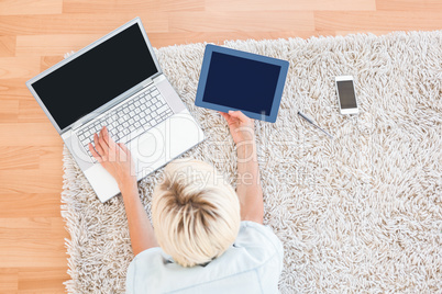 Pretty blonde woman lying on the floor while using her laptop an