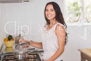 Beautiful brunette looking at saucepan