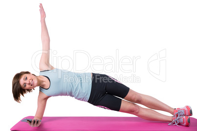 Pretty brunette looking at camera and doing side plank on exerci